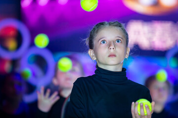 Little girl juggles balls. The circus art of juggling.