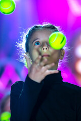 Little girl juggles balls. The circus art of juggling.