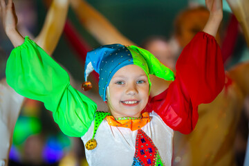A funny little girl in a clown costume is dancing.