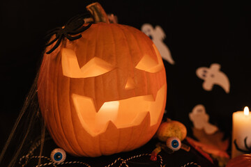 Halloween Decoratins on Table. Halloween Pumpkin. Traditional Treats. Big Scared Pumpkin Close Up. Glowing Pumpkin