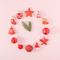 Red Christmas ornaments and fir branch on bright pink background. Creative New Year celebration concept. Minimal holiday aesthetic. Flat lay.