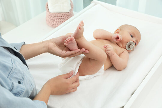 Mother changing her baby's diaper on table at home