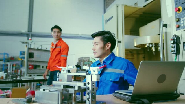 Co-working technician asian male engineer consult discussion laptop application result report discuss for quality control production line of cnc machine operate metal cutting work smart technology 