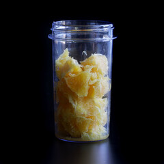 Fresh orange or grapefruit pulp in a blue transparent glass of a blender or shaker. The initial...