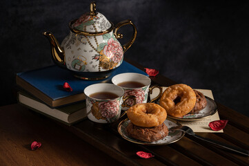 afternoon tea image with black tea,donuts and beautiful teapot and cup on board