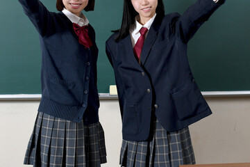 黒板の前で制服を着た笑顔の女子学生