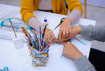 Therapist hands helping person with special needs make handmade souvenir using glue and paper