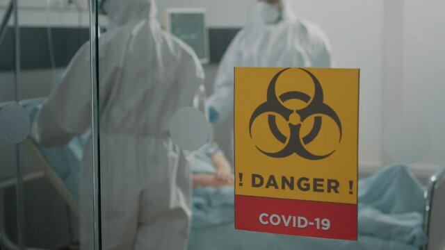 Close up of danger sign on glass of hospital ward for isolated area against coronavirus epidemic. Biohazard symbol for isolation in intensive care room at contagious zone. Outbreak of pandemic