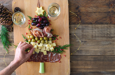 Spanish cheese and sausage board in the shape of a Christmas tree. Two people eating. Copy space.