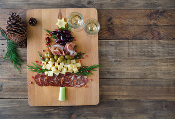Christmas tree shaped cheese and charcuterie board with wooden background. Top view. Copy space.