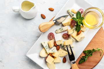 Cheese plate assortment of various types of cheese with grapes, honey and nuts, top view