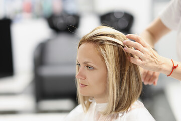 Hairdresser making hair styling to woman client in beauty salon