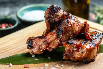 Delicious barbecued ribs seasoned with a spicy sauce and served on wooden board, Food recipe background. Close up