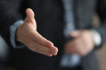 Businessman in suit stretching out his hand for handshake with partner closeup