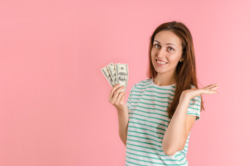 A happy brunette woman holds dollar bills in her hands and smiles. Studio shot on a pink background
