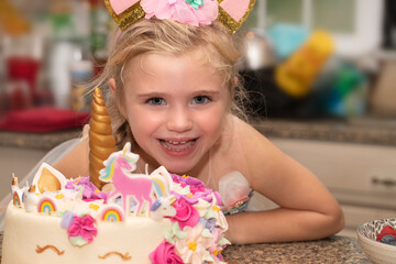 Little girl smiles next to her unicorn birthday cake © Michael O'Neill