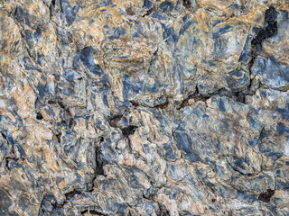 Wavy texture of the stone. Multicolored detailed texture of a rocky mountain slope. Geological rock.
