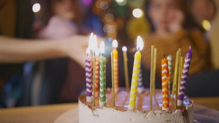 Parents burn colorful candles with gas burner on birthday cake to celebrate children holiday at table on blurred background extreme close view