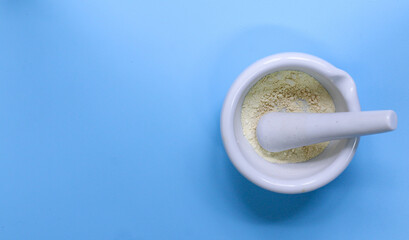 Pills are crushed in a mortar taken on a blue background, top view. Work space on the sides.