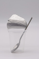 empty clear yogurt cup with aluminum foil and spoon