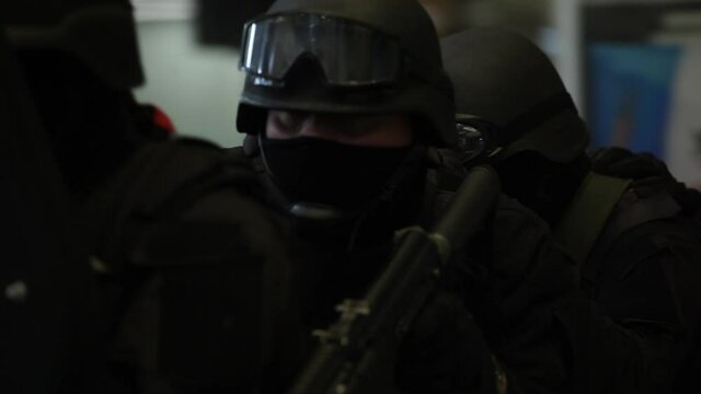 Masked team hiding behind bulletproof shield.