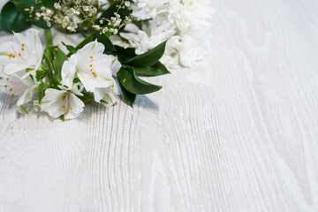 Background with white flowers and green leaf in corners on wooden white table