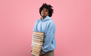 Upset African American teenager holding stack of books, looking at camera in despair, not wishing to start education © Prostock-studio