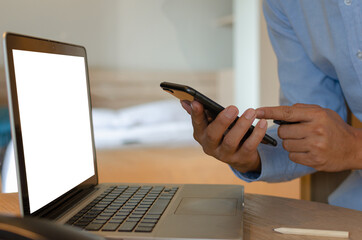 man using mobile smart phone and computer laptop on desk