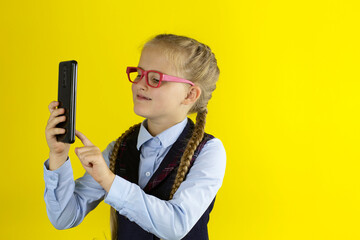 A schoolgirl with glasses communicates via video link on her smartphone