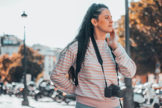 Mujer adolescente turista pensativa sobre la ciudad junto con el paisaje en Paris con su cámara fotográfica para hacer una sesión de fotos profesionales junto con su mochila y equipaje en su viaje