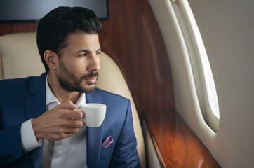 Portrait of handsome pensive middle eastern businessman drinking coffee, planning project looking...