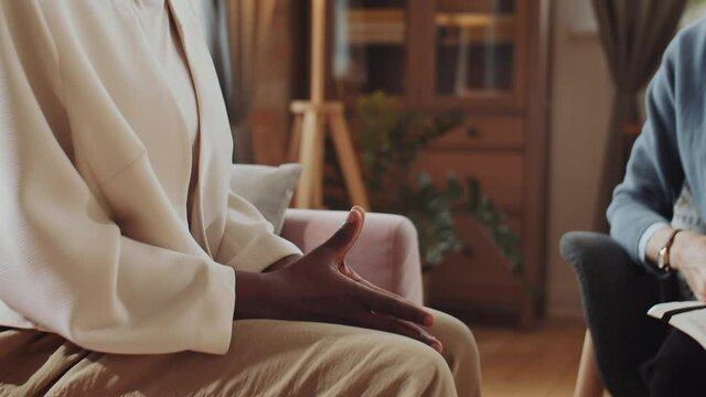 Close up shot of Caucasian psychologist putting hand on hand of African American woman while comforting patient during therapy session