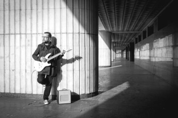 Man in black with a beard with electric guitar on urban outdoor location in summer.