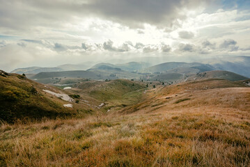 Beautiful mountains under clouds and valley with dry grass around. Natural landscape with high...