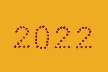 Date 2022 made with red Christmas star shaped baubles on a yellow background with copy space. Minimal New year flat lay concept.