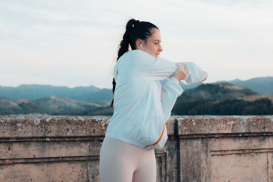 Chica joven de cabello casta&ntilde;o oscuro ejercit&aacute;ndose por la ma&ntilde;ana junto a las monta&ntilde;as haciendo una flexi&oacute;n de codos para recorrer en ruta la ciudad y quemar calor&iacute;as