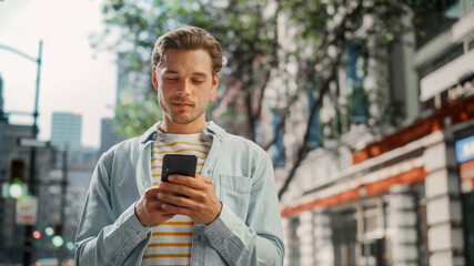 Portrait of a Handsome Young Man Wearing Casual Clothes and Using Smartphone on the Urban Street. Manager in Big City Connecting with People Online, Messaging and Browsing Internet.