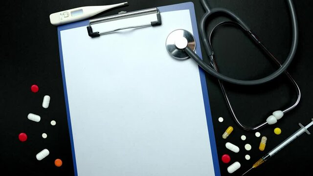 medical stethoscope, doctor's notepad, many colored pills, capsules, medicine on black background, concept of maintaining health, medication treatment, vitamins, top view. Stop motion video