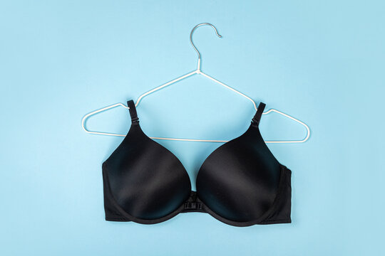 Top view of stylish women bra on white hanger on light blue background with copy space. Women's wardrobe