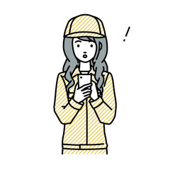 立ってスマートフォンを操作して何かに気づいて驚いた作業員の女性