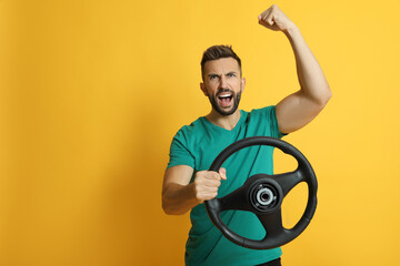 Emotional man with steering wheel on yellow background. Space for text - Powered by Adobe