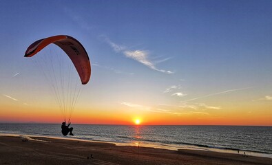 Seascape at sunset. A paraglider flying over the beach