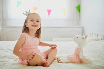 Adorable little girl dressed as princess playing with unicorn
