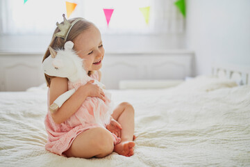 Adorable little girl dressed as princess playing with unicorn