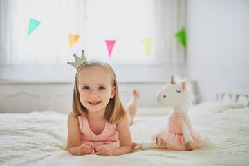 Adorable little girl dressed as princess playing with unicorn