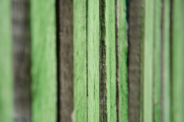 Fototapeta premium Close-up old green wooden fence with copy space. Wall of frayed wooden planks. Texture of old wooden planks with peeling paint. Background and texture for design.