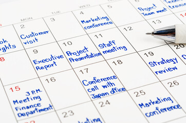 Handwriting scheduling appointments on calendar sheet.