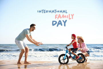 Fototapeta premium Happy parents teaching son to ride bicycle on sandy beach near sea. Happy Family Day