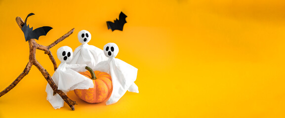 Pumpkin, gosts and bats on orange background, concept of Halloween. Banner, copy space.