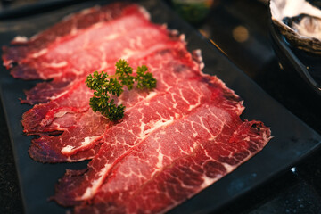 Sliced beef shabu in a black plate in a restaurant